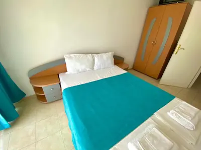 a small bedroom with a bed and a wooden cabinet at Amrita apartments Nessebar in Nesebar