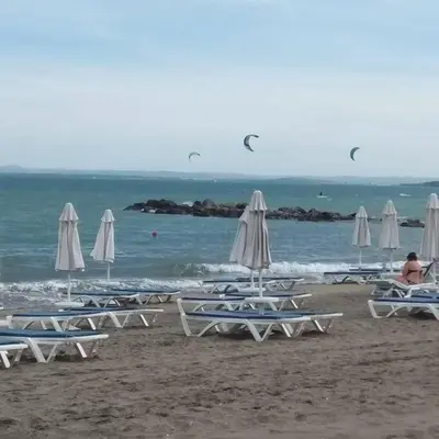 a group of lounge chairs and umbrellas on a beach at Studio in the center of Sarafovo in Burgas City