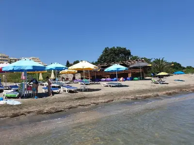 a beach with umbrellas and chairs and the water at Studio in the center of Sarafovo in Burgas City