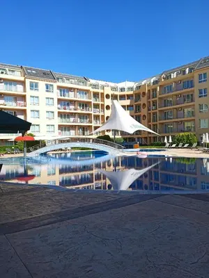 a swimming pool with some white umbrellas and some buildings at Big comfortable apartment with 2 bedrooms Pollo Resort Sunny Beach in Sunny Beach