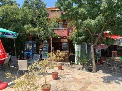 a patio with trees and chairs and a building at Апартамент Нели in Ravadinovo