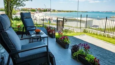 a patio with chairs and flowers and a view of a beach at Kraimorie Park in Burgas City
