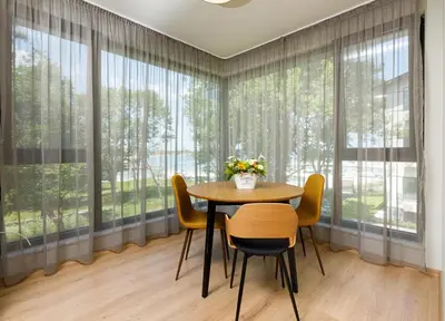 a dining room with a table and chairs and large windows at Kraimorie Park in Burgas City