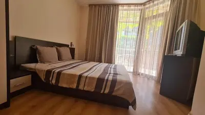 a bedroom with a bed and a tv and a window at Апартамент Лагуна Aйланд in Sozopol