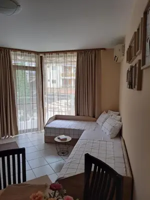 a room with two beds and a table in it at Апартамент Лагуна Aйланд in Sozopol