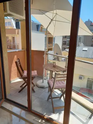 a balcony with a table and chairs and an umbrella at Perla 1 apartments in Ravda