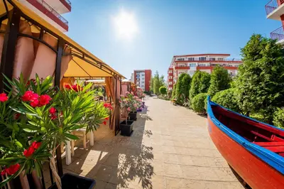 a boat on a sidewalk next to a building with flowers at Panorama Fort Beach in Sveti Vlas