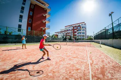 two children playing tennis on a tennis court at Panorama Fort Beach in Sveti Vlas