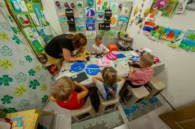 a group of children sitting at a table with a woman at Panorama Fort Beach in Sveti Vlas
