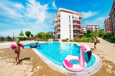 a man standing next to a swimming pool with a pink swan at Marina View Fort Beach in Sveti Vlas