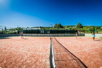 three people playing tennis on a tennis court at Marina View Fort Beach in Sveti Vlas