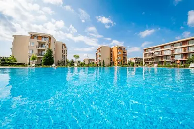 a swimming pool with blue water in front of buildings at Orchid Fort Garden in Sunny Beach