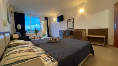 a bedroom with a large bed and a living room at ESPERANTO 401 Large Studio Sunny Beach in Sunny Beach