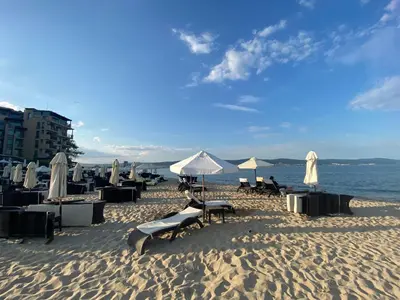 a beach with chairs and umbrellas on the sand at ESPERANTO 403 Large Studio Sunny Beach in Sunny Beach