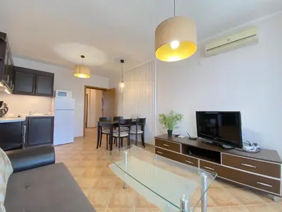a living room with a glass table and a kitchen at Cascadas Family Resort - Private apartment - BSR in Sunny Beach