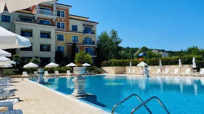 a swimming pool with chairs and umbrellas next to a building at Lily Beach - Apartment 408A in Sozopol