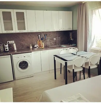 a kitchen with white cabinets and a table with chairs at Апартамент Холи in Sozopol
