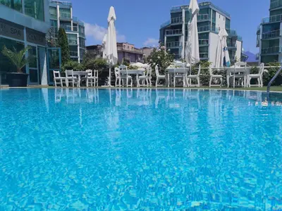 a large swimming pool with chairs and tables and buildings at F 207 Primorsko del Sol - просторно студио с кухня in Primorsko