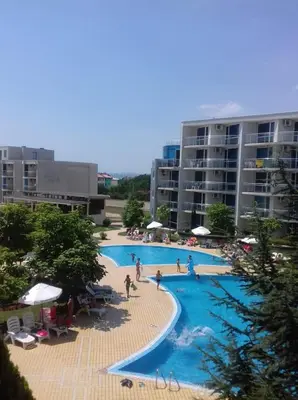 a large swimming pool with people in a resort at Apartment with green terrace in Burgas City