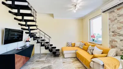 a living room with a yellow couch and a spiral staircase at Bratanov Vip Zone maisonettes 606 & 609 in Sunny Beach