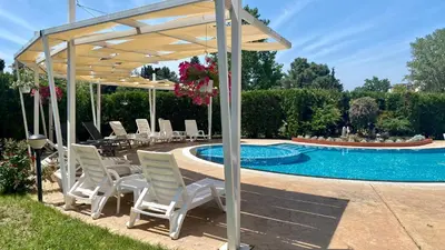 a pavilion with chairs and a table next to a pool at Bratanov Vip Zone maisonettes 606 & 609 in Sunny Beach