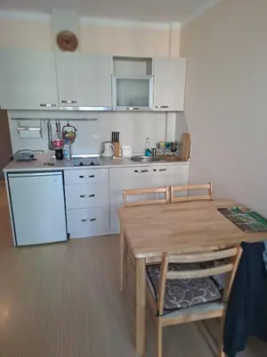 a kitchen with white cabinets and a wooden table and chairs at SUNNY BEACH PLAZA Apartments in Sunny Beach