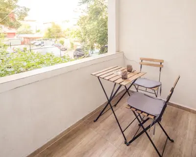 a table and two chairs on a balcony with a window at Aleks Sunrise -Top Center ,Sea Garden in Burgas City