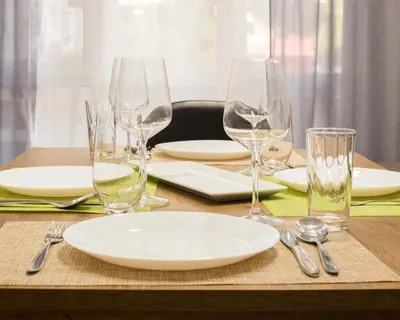 a table with a plate and wine glasses on it at Aleks Sunrise -Top Center ,Sea Garden in Burgas City