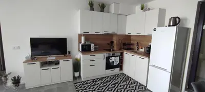 a kitchen with white cabinets and a tv and a refrigerator at Antique 7 ap.1 in Sozopol
