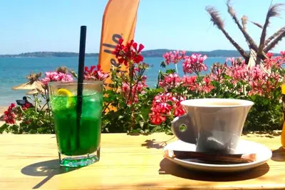 a drink and a cup on a wooden table with the ocean at Happy-U house - Modern and with stunning view in Chernomorets
