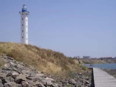a lighthouse on a hill next to a body of water at STUDIO DELUXE IN MARINA CAPE 4 stars complex 33 7 in Aheloy