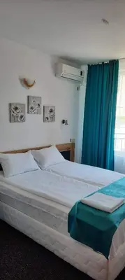 a bedroom with a large bed with blue curtains at Къща за гости Вивиан in Kiten