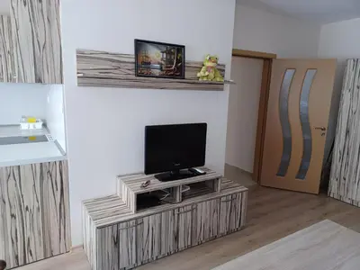 a living room with a tv on a wooden stand at Апартамент Желева in Pomorie