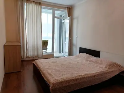 a bedroom with a bed and a large window at Апартамент Даскала с паркомясто in Burgas City