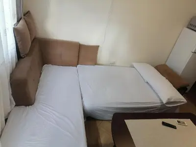a bed with two pillows and a table in a room at Апартамент Даскала с паркомясто in Burgas City