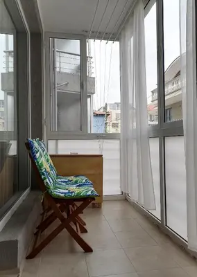 a chair sitting in a room with windows at Апартамент Даскала с паркомясто in Burgas City