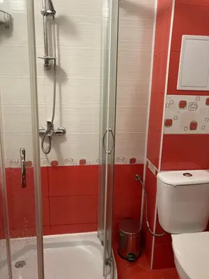 a bathroom with a shower with a toilet and red walls at Апартамент Даскала с паркомясто in Burgas City