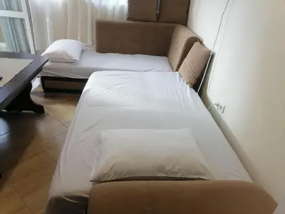 a couple of beds in a room with a desk at Апартамент Даскала с паркомясто in Burgas City