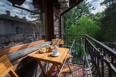 a wooden table on a balcony with food on it at Къща за гости Димови in Sozopol