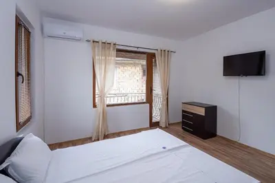 a bedroom with a white bed and a television at Къща за гости Димови in Sozopol