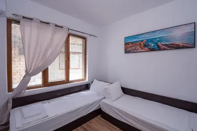 a living room with a couch and two windows at Къща за гости Димови in Sozopol