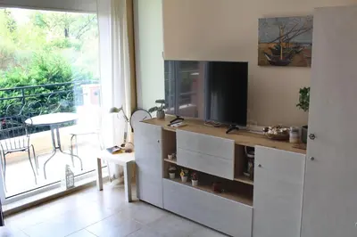 a living room with a entertainment center with a television at Pomorie Residence 1-bedroom apartment with pool & free parking, 300 m to the beach in Pomorie