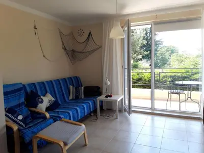 a living room with a blue couch and a sliding glass door at Pomorie Residence 1-bedroom apartment with pool & free parking, 300 m to the beach in Pomorie