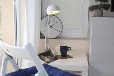 a table with a chair and a clock on the wall at Pomorie Residence 1-bedroom apartment with pool & free parking, 300 m to the beach in Pomorie