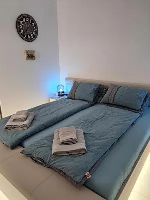 a large bed with two pillows and a clock on the wall at Salvia in Ravda