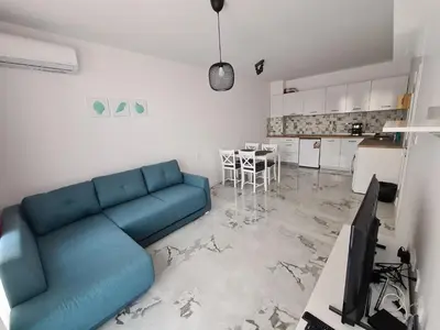 a living room with a blue couch and a kitchen at Dolphin beach apart Obzor in Obzor
