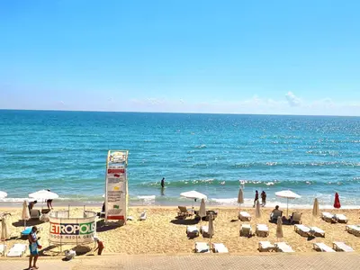 a beach with chairs and umbrellas and the ocean at Cactus beach apart Obzor in Obzor
