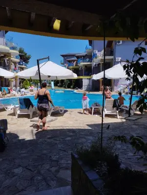 a woman walking next to a swimming pool with umbrellas at Casa do Farol - апартамент с басейн до плажа на къмпинг 