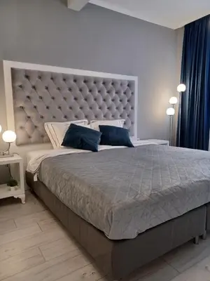 a bedroom with a large bed with a large headboard at Tara Deluxe Apartment in Varna City