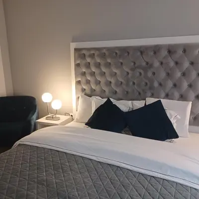 a bedroom with a large bed with a large headboard at Tara Deluxe Apartment in Varna City